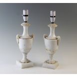 A pair of alabaster lamp bases, each of classical two handled urn form, raised on square plinth