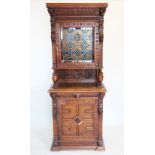 A late 19th century French oak and stained glass cabinet, with a moulded cornice above a carved