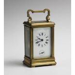 An early 20th century brass cased carriage clock, with a shaped swing handle above the visible