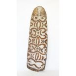 An Asmat shield, Papua New Guinea, carved in relief with tribal motifs upon a white ground, 215cm x