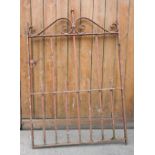 A wrought iron garden gate, with a scroll work top rail above wrought iron uprights of square