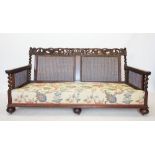 An early 20th century walnut three piece bergere suite, comprising a three seater settee, with a
