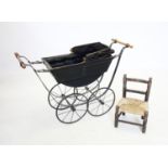 A Victorian style dolls pram and dolls chair, the black painted boat shaped pram mounted on a iron