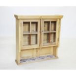 A glazed pine wall cupboard, early 20th century, the glazed doors above a single shelf inset with