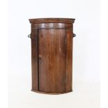A late 19th century oak hanging bow front corner cupboard, of small proportions, the single door