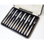 A cased set of six fruit knives and six forks, of plain polished form with shaped terminals, the