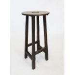 An early 20th century oak clerks stool, the oval seat with an 'S' shaped aperture, raised upon