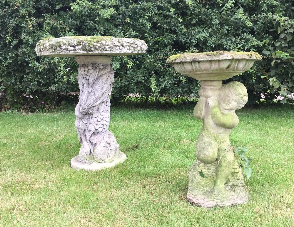 A reconstituted stone bird bath, designed as a cherub supporting a bowl shaped bath, 62cm high, with