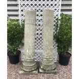 A pair of reconstituted stone garden temple columns, the plain circular columns upon carved bases