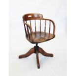 An early 20th century oak revolving office chair, the down swept top rail raised upon slender turned