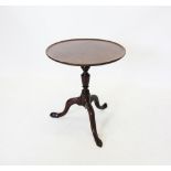 A George III mahogany tripod table, the circular top raised upon a reduced baluster turned column