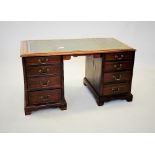 An early 20th century mahogany twin pedestal desk, the rectangular moulded top with a gilt tooled