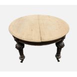 A Victorian oak scrub top extending dining table, the circular moulded top raised upon leaf carved