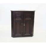 A George III oak and mahogany cross banded flat front hanging corner cupboard, the pair of two panel