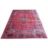 A large red ground Persian Mashad carpet with traditional medallion design and unique colours, 390cm