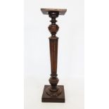 A late 19th century mahogany torchere, the square top raised upon a fluted and tapering column, upon