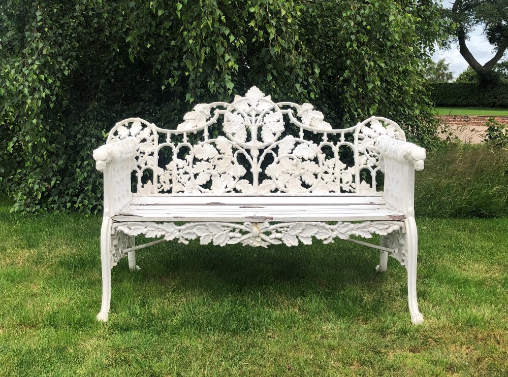 A Coalbrookdale style bench, oak leaf pattern, the white painted cast iron bench with wooden slatted