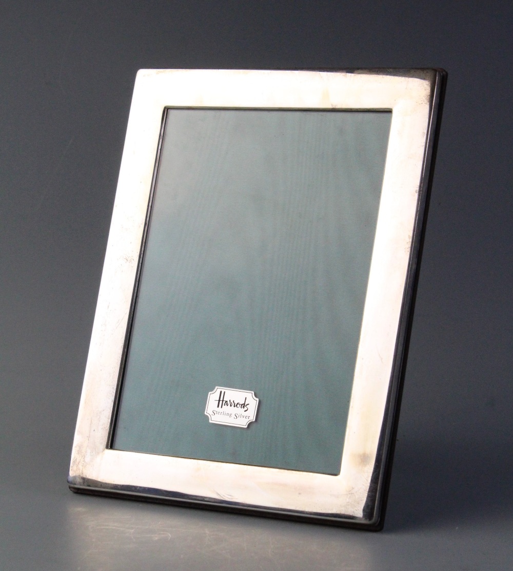 A white metal photograph frame, of rectangular form with plain polished borders, wooden backing