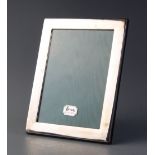 A white metal photograph frame, of rectangular form with plain polished borders, wooden backing
