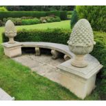 A large reconstituted stone garden bench, the curved bench with three scroll supports, terminating