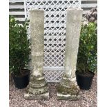 A pair of reconstituted stone garden temple columns, the plain tapering circular columns upon carved