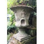 A reconstituted stone garden urn in the from of the Warwick vase, decorated in relief with a