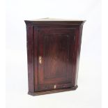 A George III oak flat front hanging corner cupboard, the single door centred with an inlaid conch