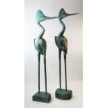A pair of decorative wooden carvings, each modelled as stylised herons, set to D shaped plinths,