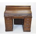 An early 20th century oak roll top desk, the 'S' shaped tambour front enclosing a