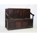 A late 17th/early 18th century oak box settle, with four inverted panels above the hinged box