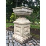 A pair of reconstituted stone plinths, each of square form with recessed side panels, 42cm high,