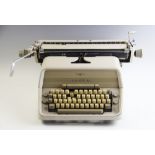 A mid 20th century West German Adler typewriter, with sliding carriage, complete with branded cover,