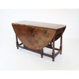 An 18th century oval oak gate leg dining table, the moulded plank top above a single frieze