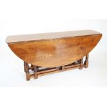 A 17th century style oak drop leaf wake table, late 20th century, the oval top raised upon ring