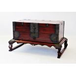 A Chinese iron bound chest on stand, with a hinged cover and vacant interior, above a central drawer