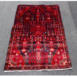A full pile Iranian village rug, with all over design against a blue and red ground, authentic