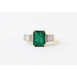 An emerald and diamond ring, the central step cut emerald weighing approx. 3.15 carats, measuring