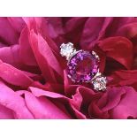 A pink sapphire and diamond ring, the central oval cut untreated vivid pink sapphire measuring