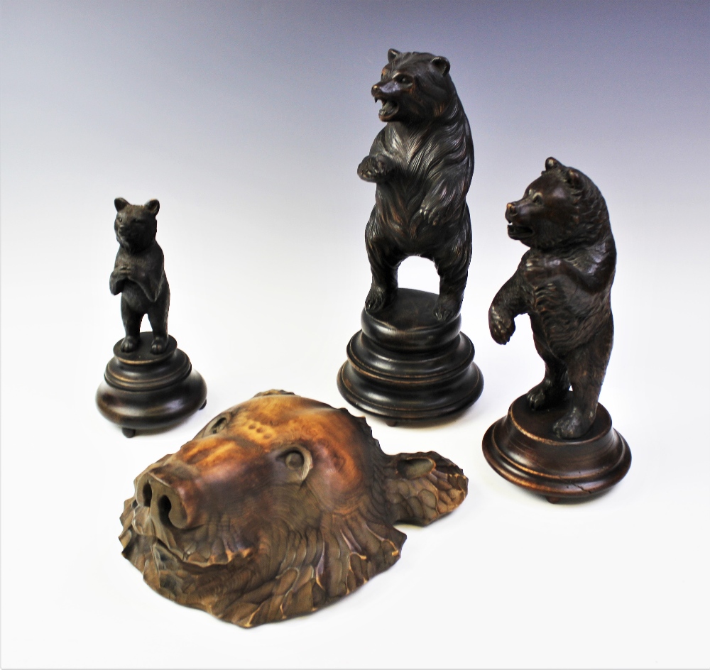 Three graduated Black Forest carvings of bears, each modelled standing upon a turned integral