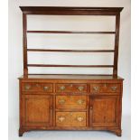 A George III oak Welsh dresser, the open plate rack with a moulded cornice above three shelves, upon