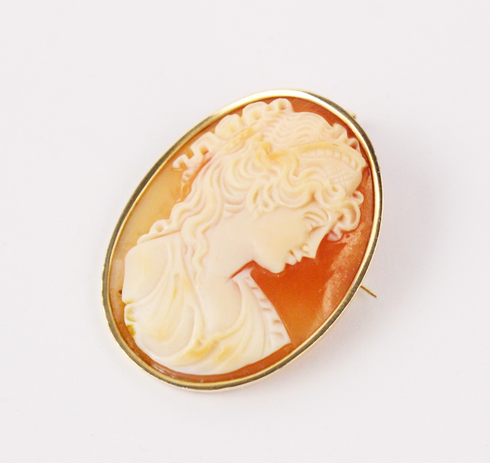 A carved shell cameo brooch pendant, the oval cameo depicting a woman in classical Greek attire, set