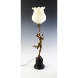 An Art Deco figural table lamp, early 20th century, the tulip shaped milk glass shade supported by a