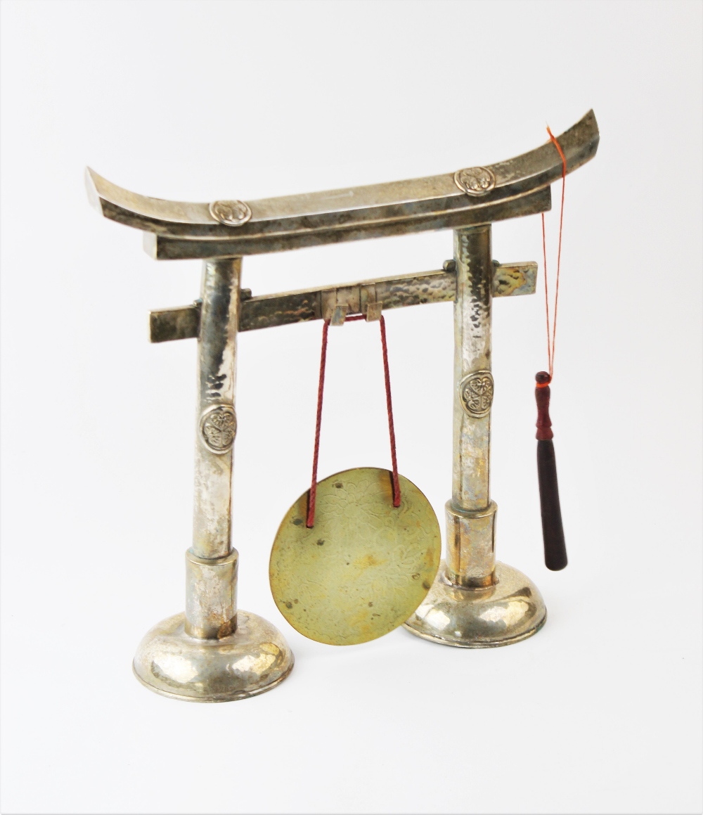 A large white metal Chinese dinner gong, modelled as a paifang suspending a polished brass plate,