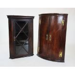 A George III oak bow front hanging corner cupboard, the pair of doors on 'H' brass hinges