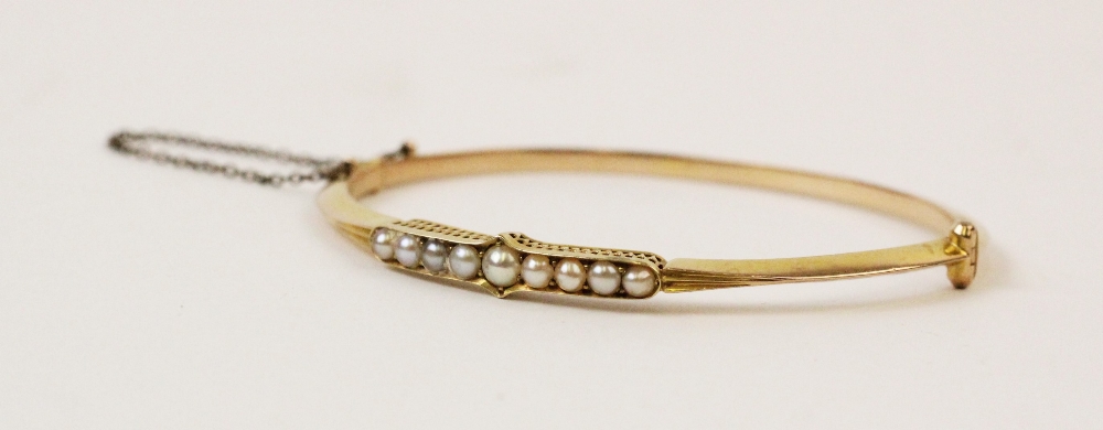 An early 20th century pearl set bangle, the central panel comprising nine cultured pearls claw set