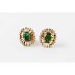 A pair of emerald and diamond cluster earrings, each comprising an oval faceted emerald measuring