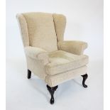 A George III style wing back armchair, early 20th century, with padded wing backs over padded scroll