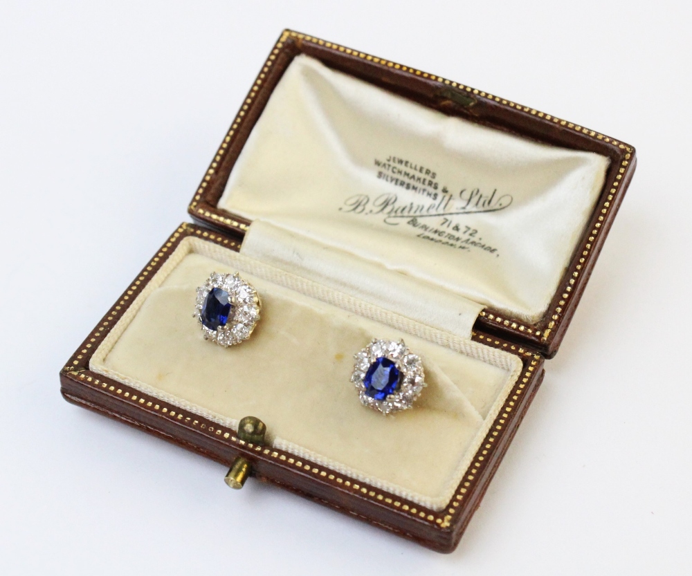 A pair of Edwardian sapphire and diamond cluster earrings, each comprising a cushion cut untreated