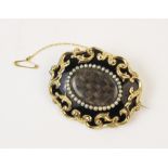 A Victorian mourning brooch, of oval form with black enamel backing and a yellow metal scrolling