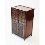 A Chinese specimen cabinet, 20th century , with eight drawers over two cupbaord doors applied with